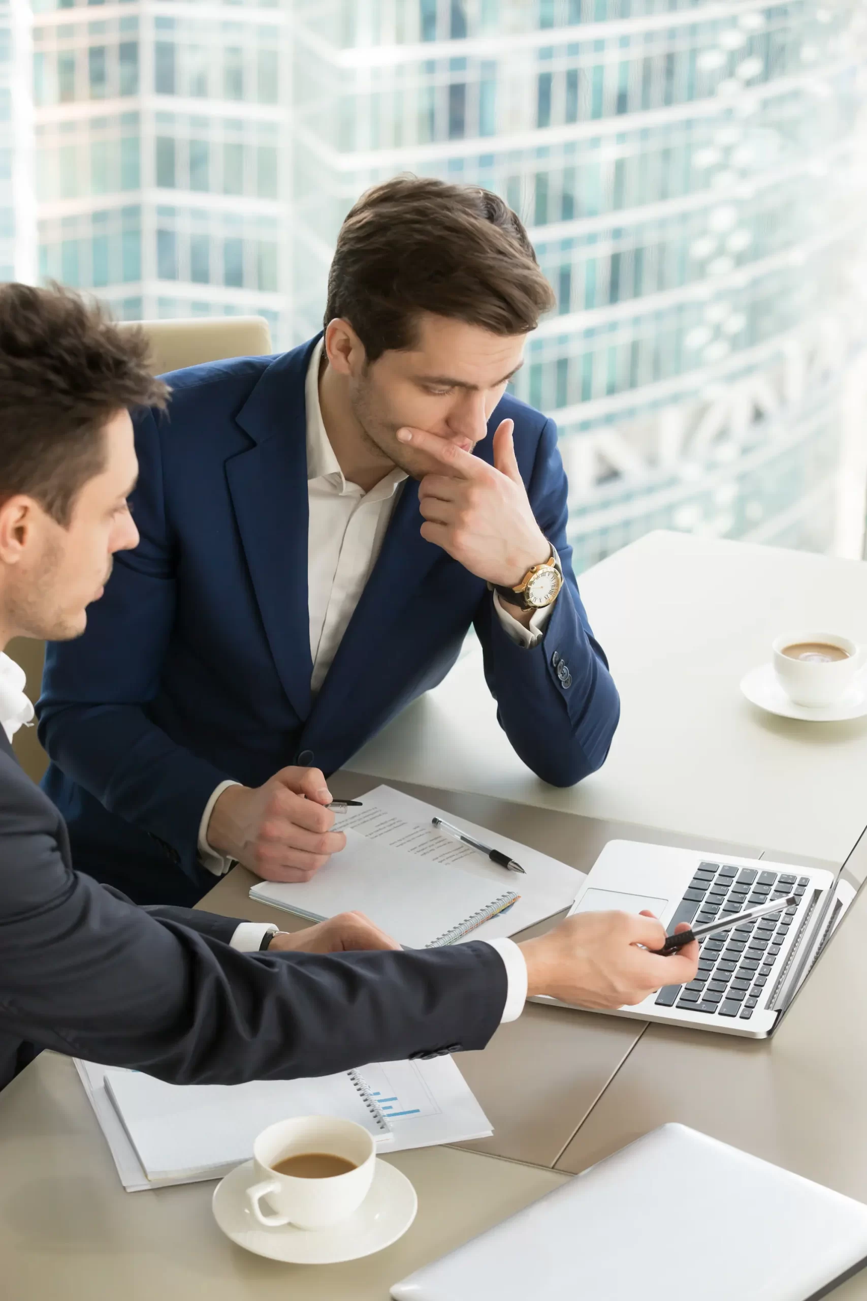 Financial consultants in a business meeting at a modern office in Portugal, analyzing strategies on a laptop, showcasing Nova Capital's professional and dedicated guidance.