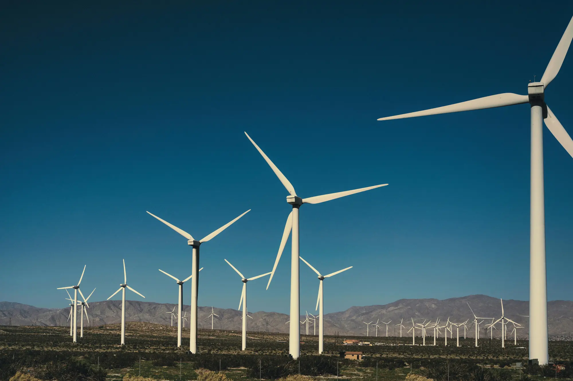Modern wind farm in Portugal with white turbines against a blue sky, showcasing the country's leadership in renewable energy and commitment to sustainability.