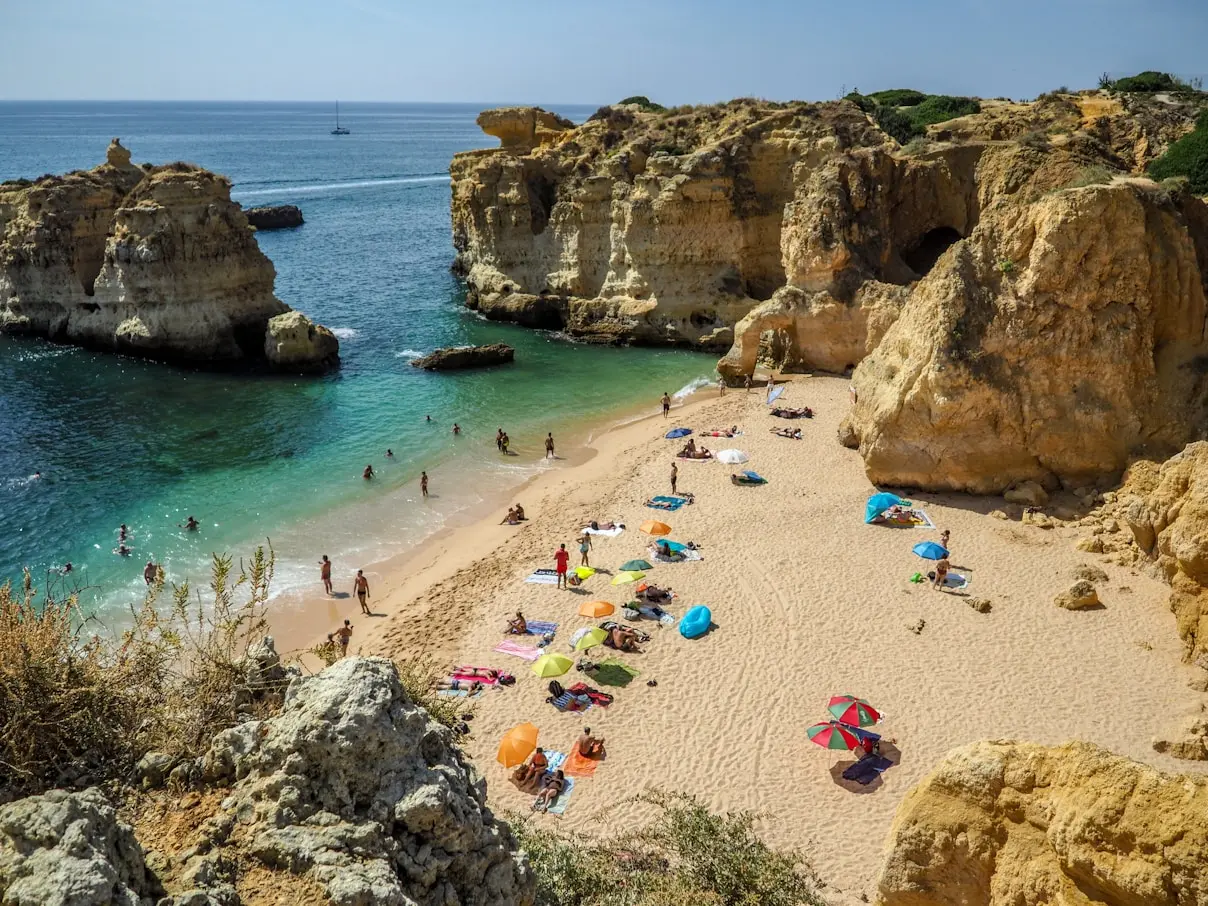 Stunning secluded beach cove with golden cliffs and turquoise waters in the Algarve, Portugal, showcasing the idyllic coastal lifestyle for potential residents.