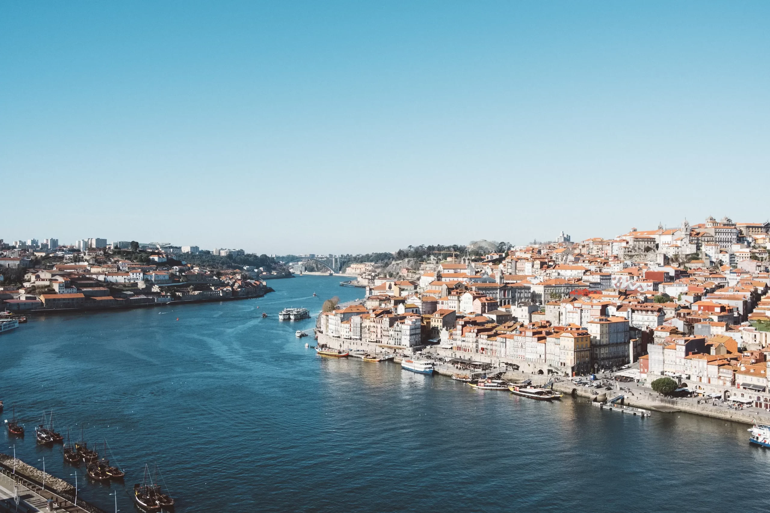 Panoramic view of Porto's historic Ribeira district and Douro River with traditional boats, showcasing Portugal's cultural heritage and vibrant urban charm.