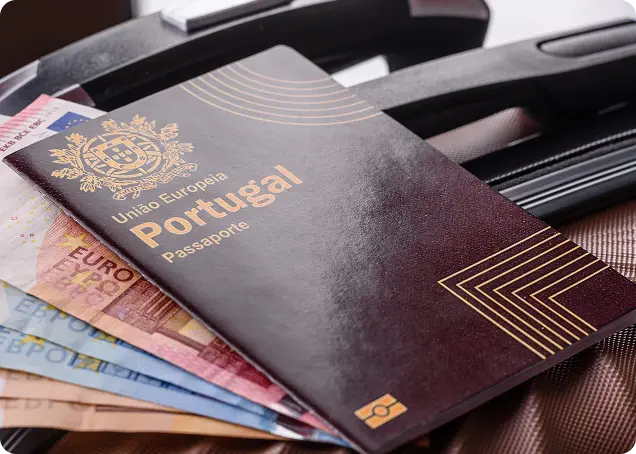 Portuguese passport resting on Euro banknotes, illustrating the financial investment requirements for the Golden Visa program.